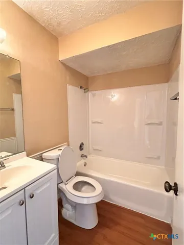 a bathroom with a bathtub shower sink vanity mirror and toilet