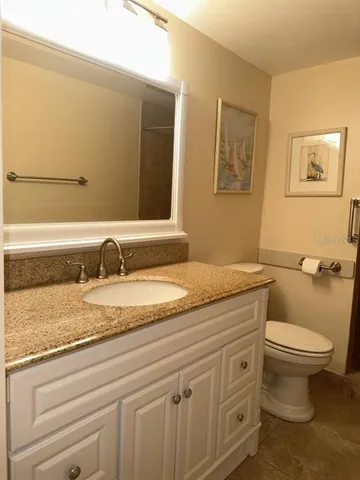a bathroom with a granite countertop toilet sink and mirror