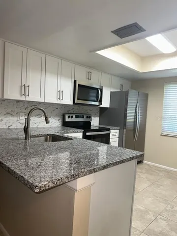 a kitchen with stainless steel appliances granite countertop a sink refrigerator and microwave