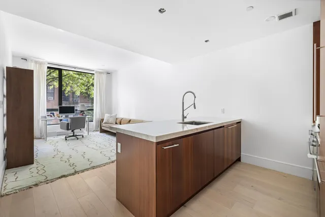a living room with stainless steel appliances granite countertop a sink and a refrigerator