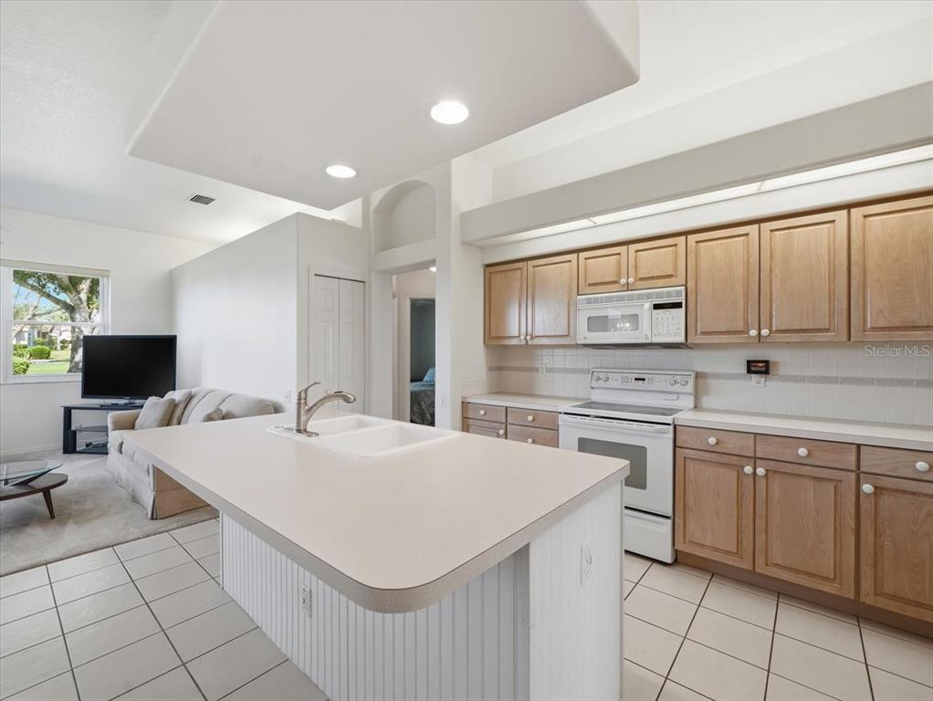 9311 Butler Boulevard Weeki Wachee, FL 34613 - Photo 34 of 60 a large white kitchen with a stove a sink a refrigerator and white cabinets with wooden floor