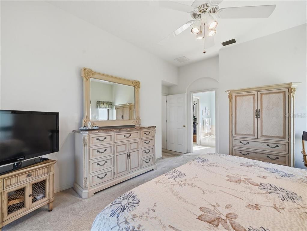 9311 Butler Boulevard Weeki Wachee, FL 34613 - Photo 45 of 60 a bedroom with a bed and a flat screen tv in white cabinets