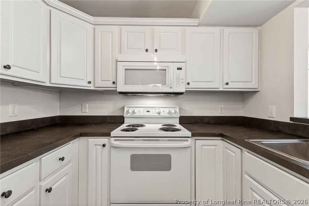 1221 Westview Lane, Unit 301 Raleigh, NC 27605 - Photo 27 of 32 a kitchen with white cabinets and white appliances