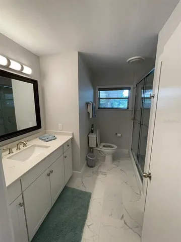 a bathroom with a granite countertop sink a toilet and shower