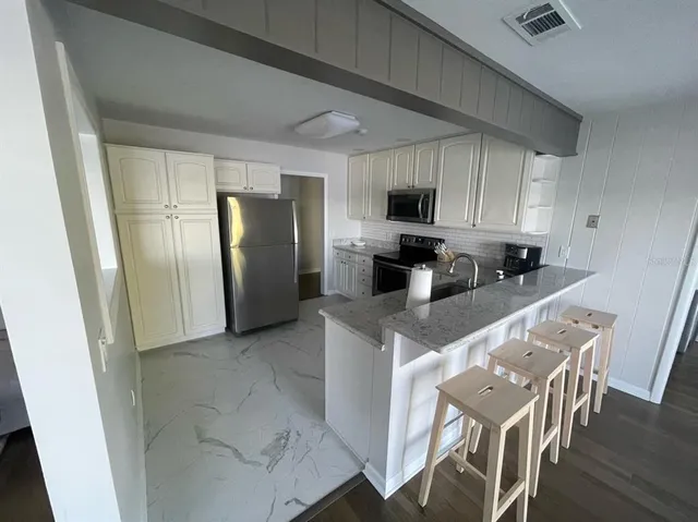 a kitchen with stainless steel appliances granite countertop a refrigerator stove microwave and sink