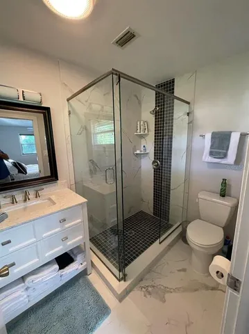 a room with a bed mirror and glass door