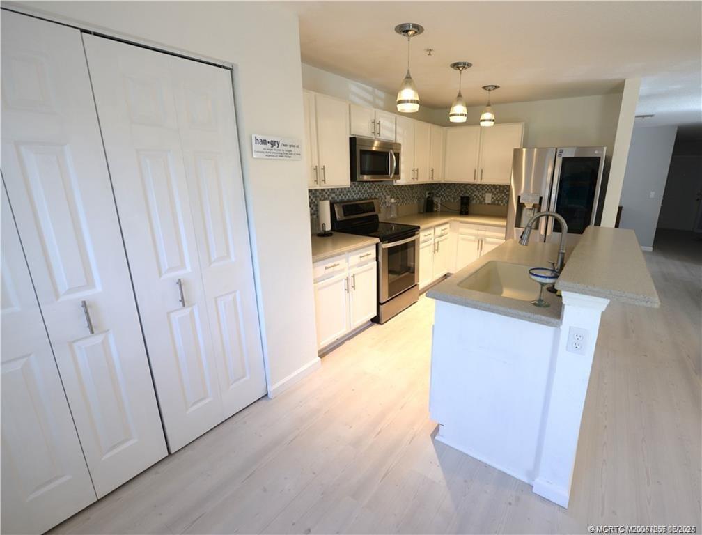 324 Southeast Bloxham Way Stuart, FL 34997 - Photo 30 of 35 a kitchen with kitchen island a sink a stove a refrigerator and a stove