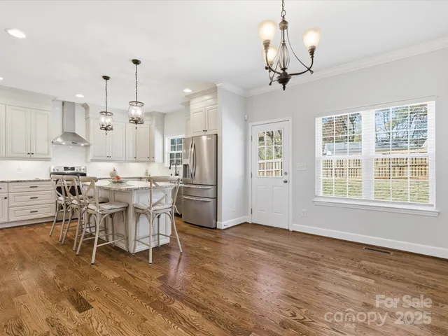 a view of a dining room and livingroom with furniture wooden floor a chandelier