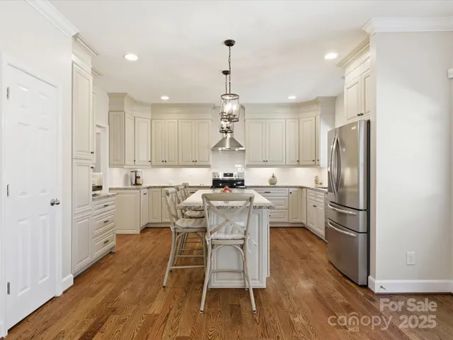 a kitchen with a refrigerator a white cabinets and wooden floor