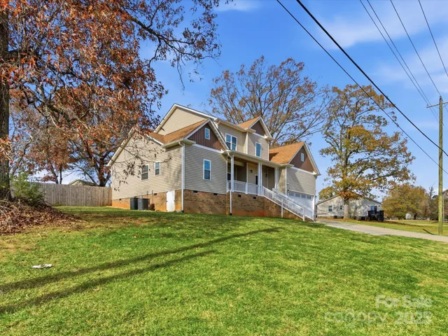 a house that is sitting in the grass with large trees