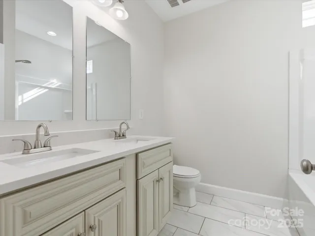 a bathroom with a granite countertop sink a toilet and a mirror