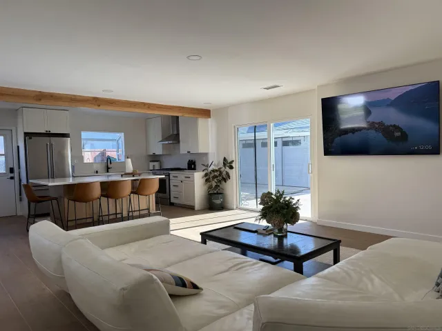 a living room with furniture a flat screen tv and kitchen view
