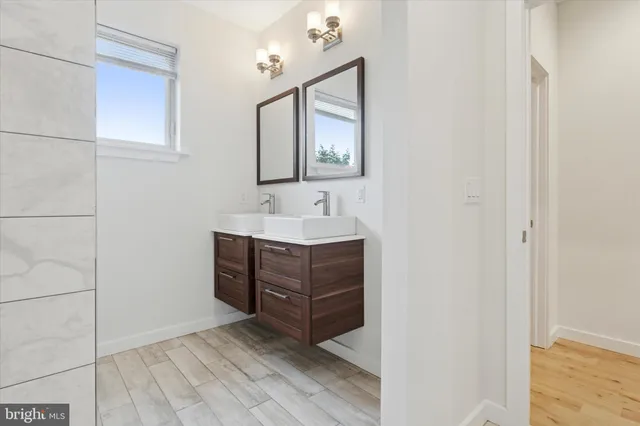 a view of a hallway with wooden floor and a bathroom