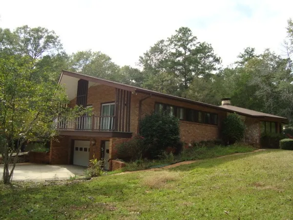 a backyard of a house with wooden fence and large trees