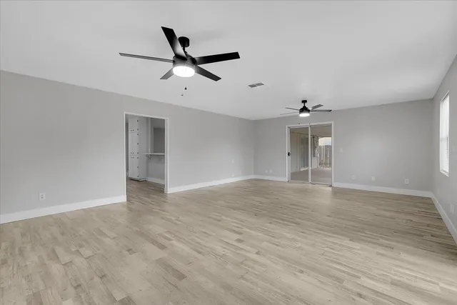 a view of empty room with wooden floor and ceiling fan