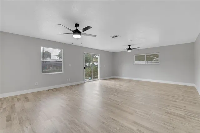a view of an empty room with a window and wooden floor