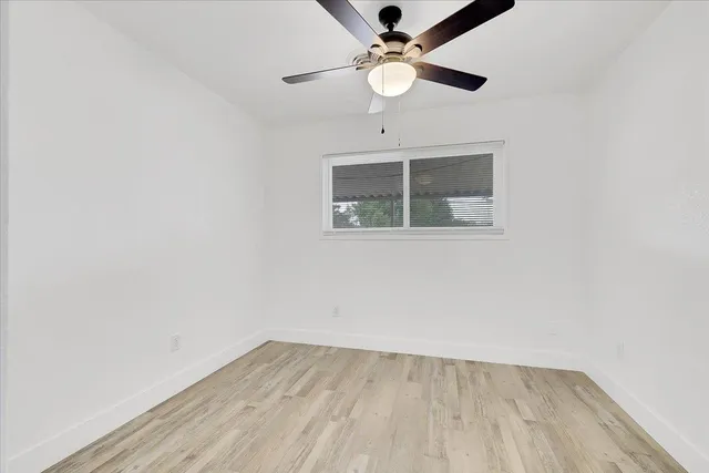an empty room with a window and a fan