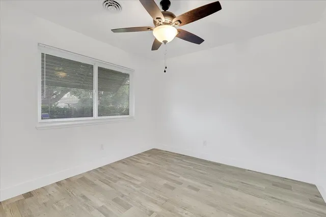 an empty room with a window and a fan