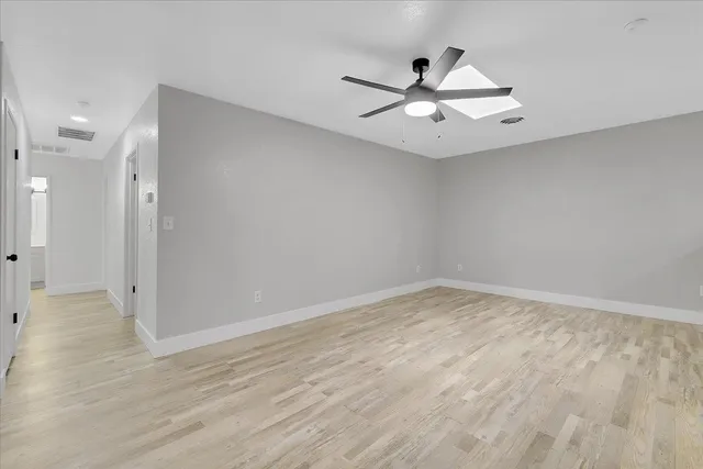 an empty room with wooden floor and ceiling fan