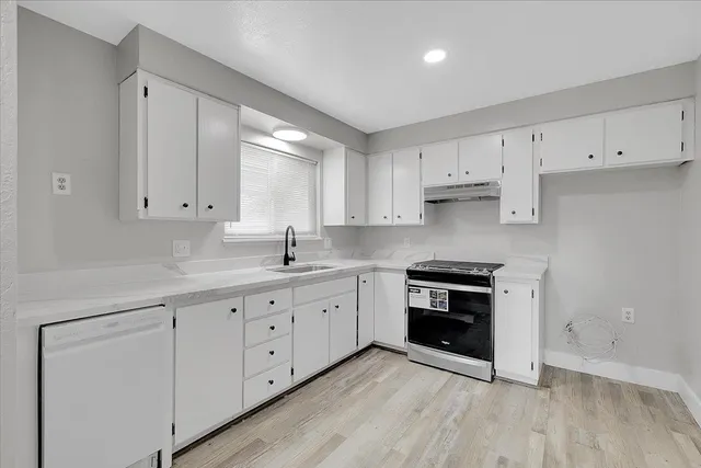 a kitchen with granite countertop white cabinets and stainless steel appliances