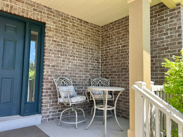 369 Culross Circle Tooele, UT 84074 - Photo 50 of 54 Covered porch featuring a dark teal entry door with sidelight, brick facade, stucco column, and white railings
