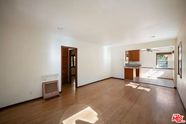 a view of a livingroom with wooden floor and a refrigerator