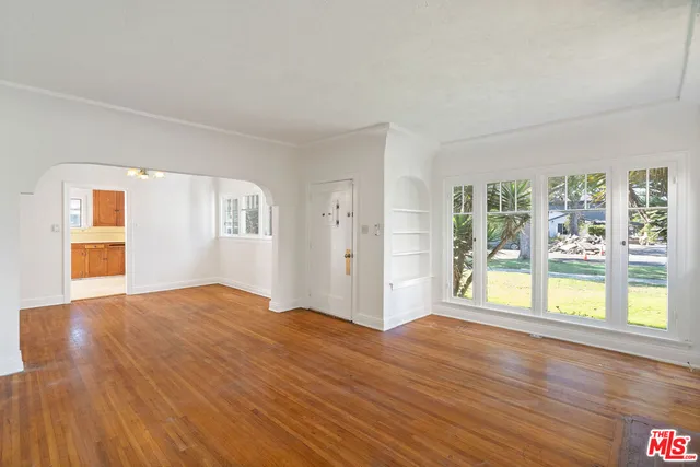 a view of an empty room with a window and wooden floor