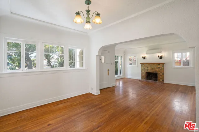 a view of a livingroom with a fireplace wooden floor and chandelier