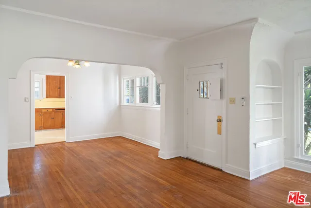 a view of an empty room with wooden floor and a window