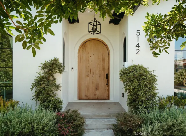 a view of a door of the house with a tree
