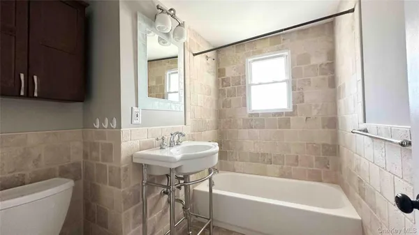 a white bath tub sitting next to a white sink and a mirror