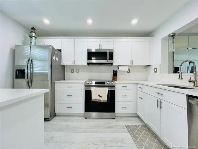 a kitchen with white cabinets and stainless steel appliances