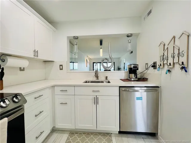 a kitchen with white cabinets and sink