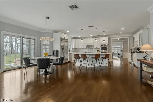 a open kitchen with stainless steel appliances granite countertop a stove a refrigerator a kitchen island and chairs with wooden floor