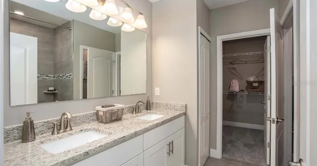 a bathroom with a granite countertop double vanity sink and a mirror