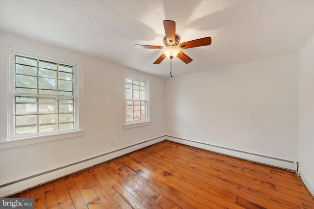 a view of empty room with wooden floor and fan