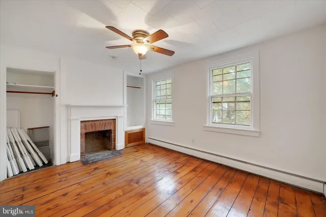 a view of an empty room with wooden floor fireplace and a window