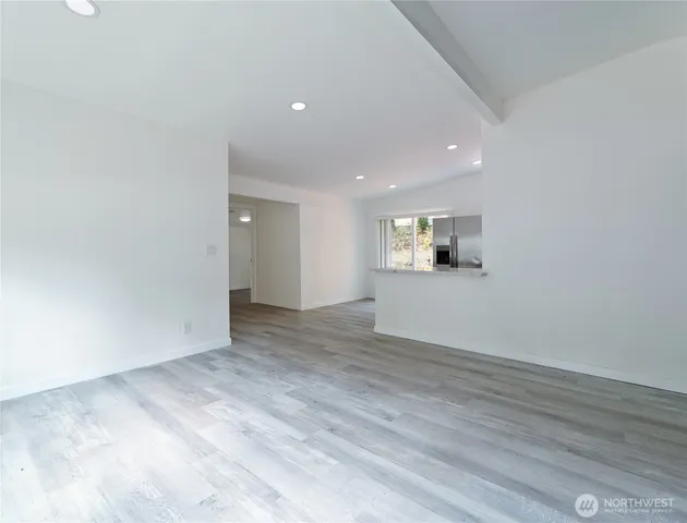 a view of a big room with wooden floor and windows