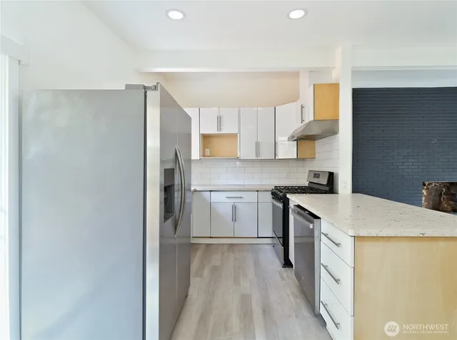 a kitchen with a sink a stove a refrigerator and white cabinets