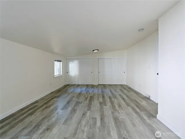 an empty room with a hardwood and windows