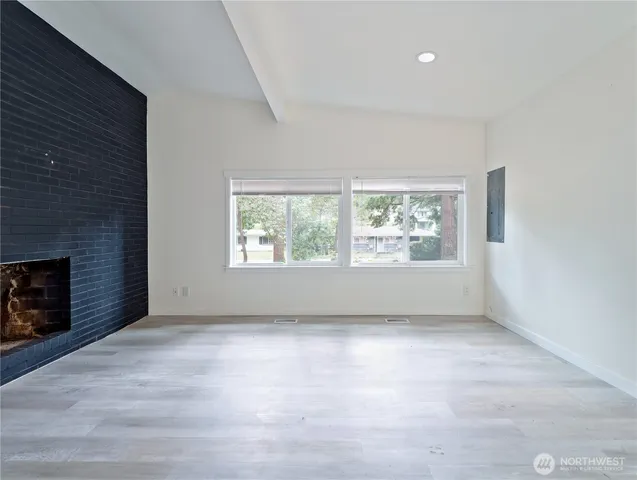 an empty room with windows and fireplace