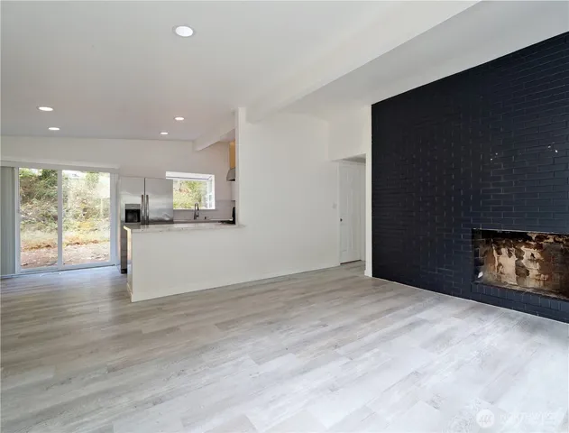 a view of an empty room with a window and fire place