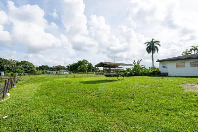a view of a house with a big yard and a large trees