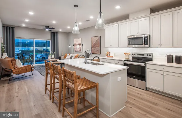 a kitchen with stainless steel appliances kitchen island granite countertop a sink a stove a dining table and chairs