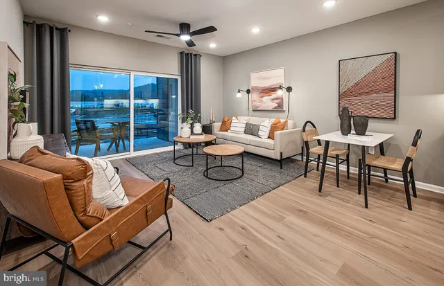 a living room with furniture a large window and wooden floor