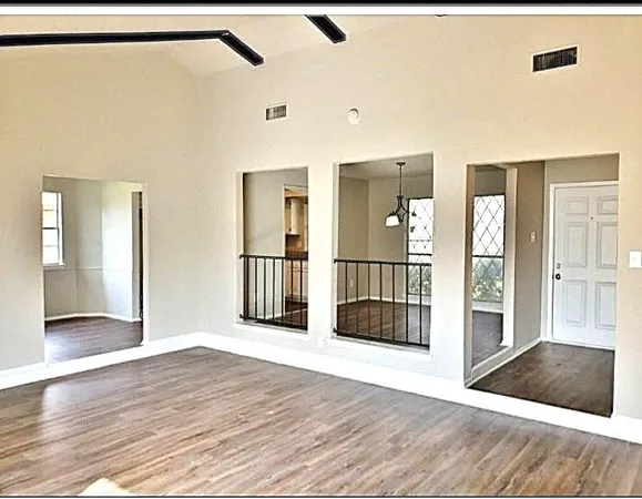 a view of a big room with wooden floor and windows