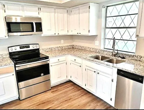 a kitchen with granite countertop white cabinets and appliances