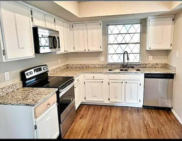 a kitchen with granite countertop wooden cabinets and white appliances