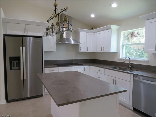 a kitchen with stainless steel appliances granite countertop a sink a stove a refrigerator a center island and cabinets