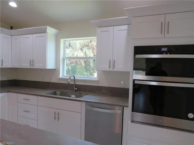 a kitchen with granite countertop white cabinets appliances and a sink